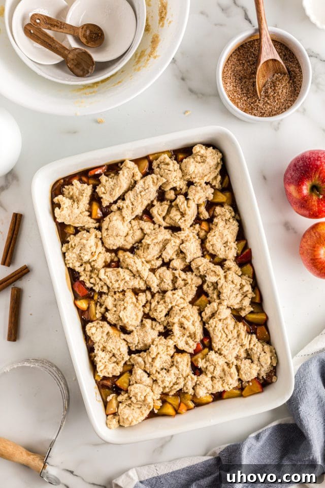 An overhead view of the biscuit topping artfully dropped in dollops over the Brown Sugar Apple Cobbler filling, ready for its final flourish.