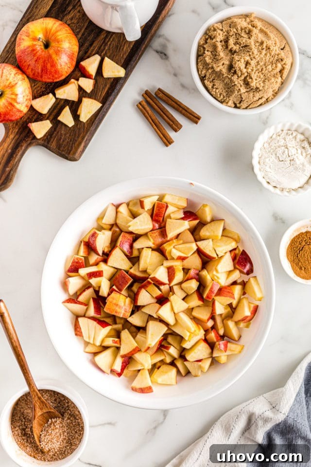 An overhead view of freshly chopped apples, ready for the cobbler filling, neatly arranged in a white mixing bowl.