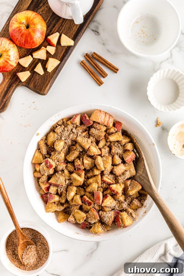 An overhead shot of the apple cobbler filling mixture, beautifully coated with brown sugar and cinnamon, in a white mixing bowl, ready for cooking.