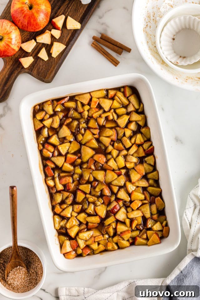 An overhead view of the delicious Brown Sugar Apple Cobbler filling, evenly spread in a white rectangular baking pan, awaiting its topping.