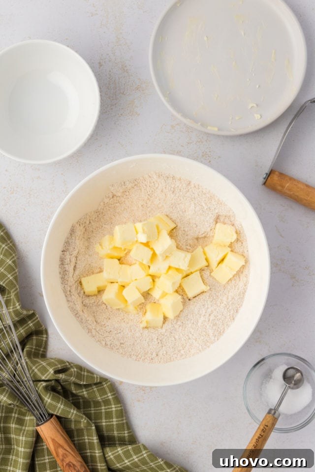 Overhead view of butter cubes added to bowl of dry ingredients