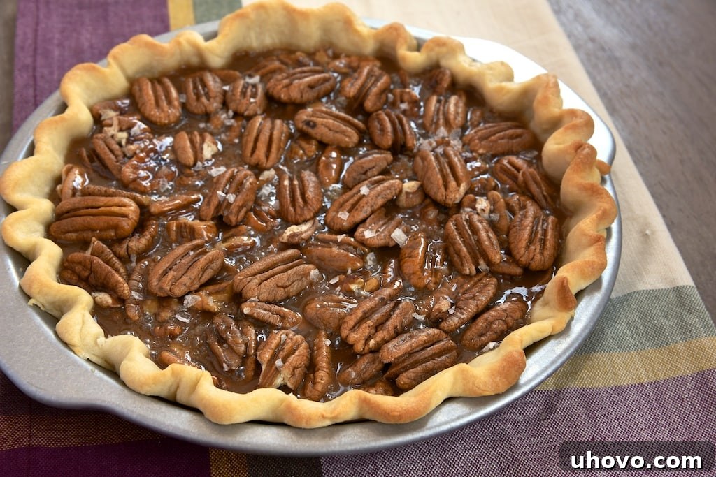 A rich, gooey, and salty caramel coating crunchy pecans, elegantly displayed as part of a Salted Caramel Pecan Pie slice, a truly irresistible dessert.