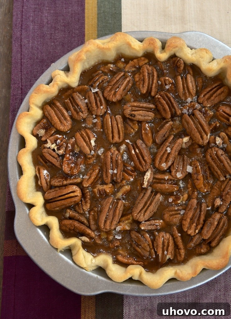 Salted caramel pecan pie, whole, in a pie dish, ready to be sliced.