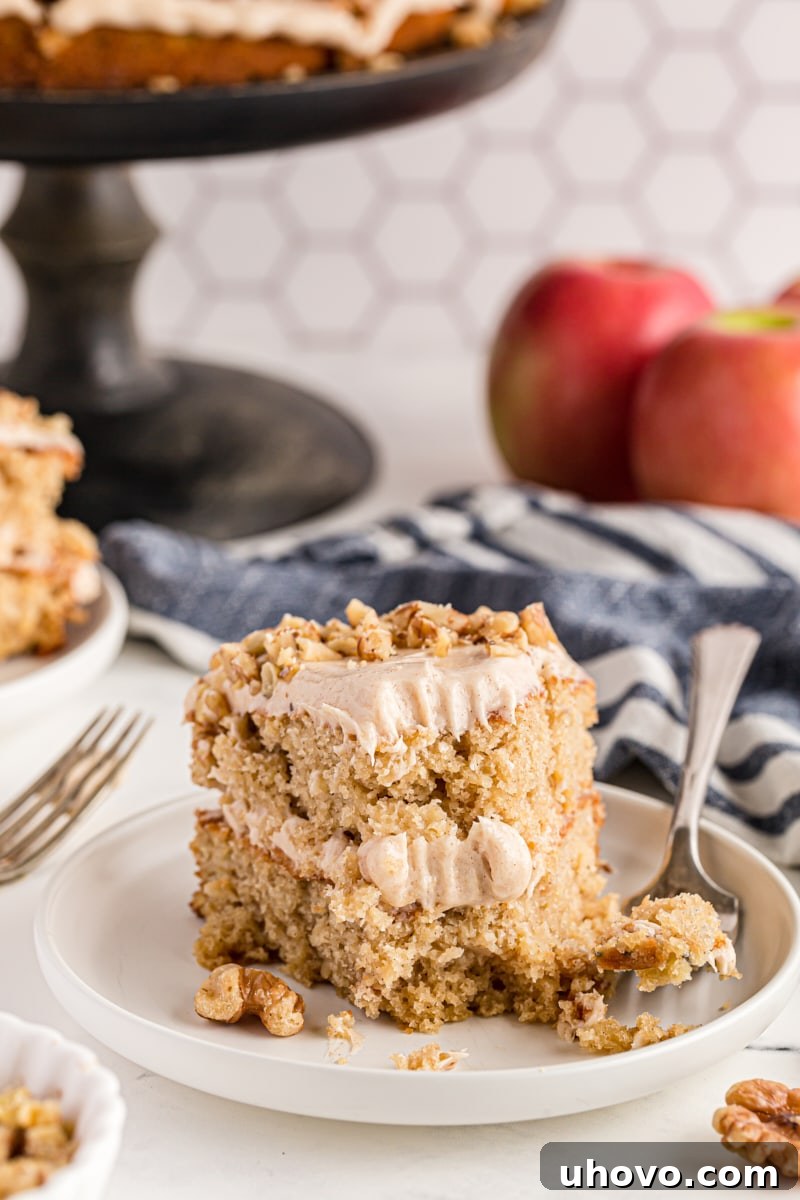 A perfectly sliced Apple Spice Cake with a bite on a fork, showcasing its moist texture and rich frosting
