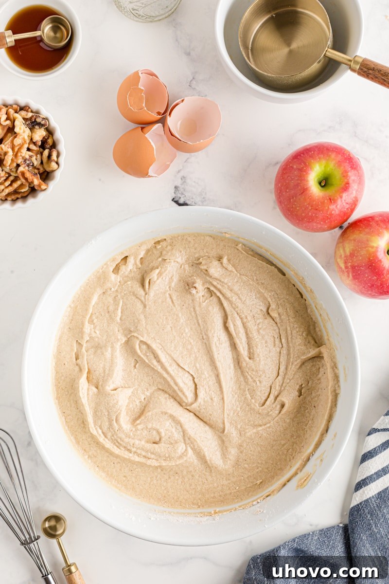 Overhead view of the thoroughly mixed cake batter in a white mixing bowl before adding apples