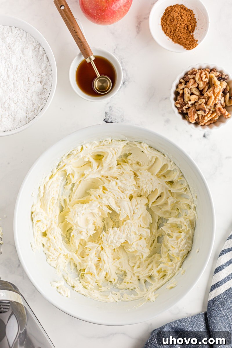 Overhead view of smoothly mixed butter and cream cheese in a white mixing bowl, ready for sugar
