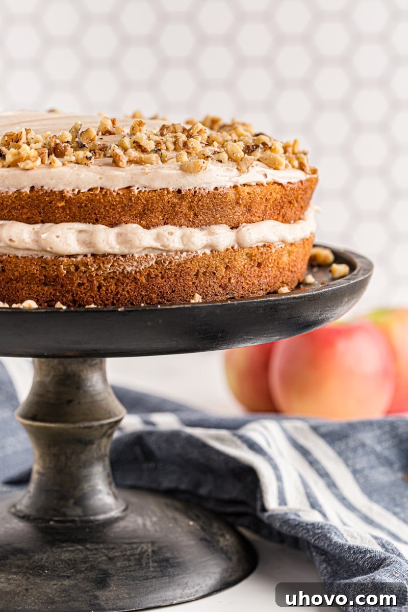 A beautifully decorated Apple Spice Cake with Cinnamon Cream Cheese Frosting on an elegant black cake stand
