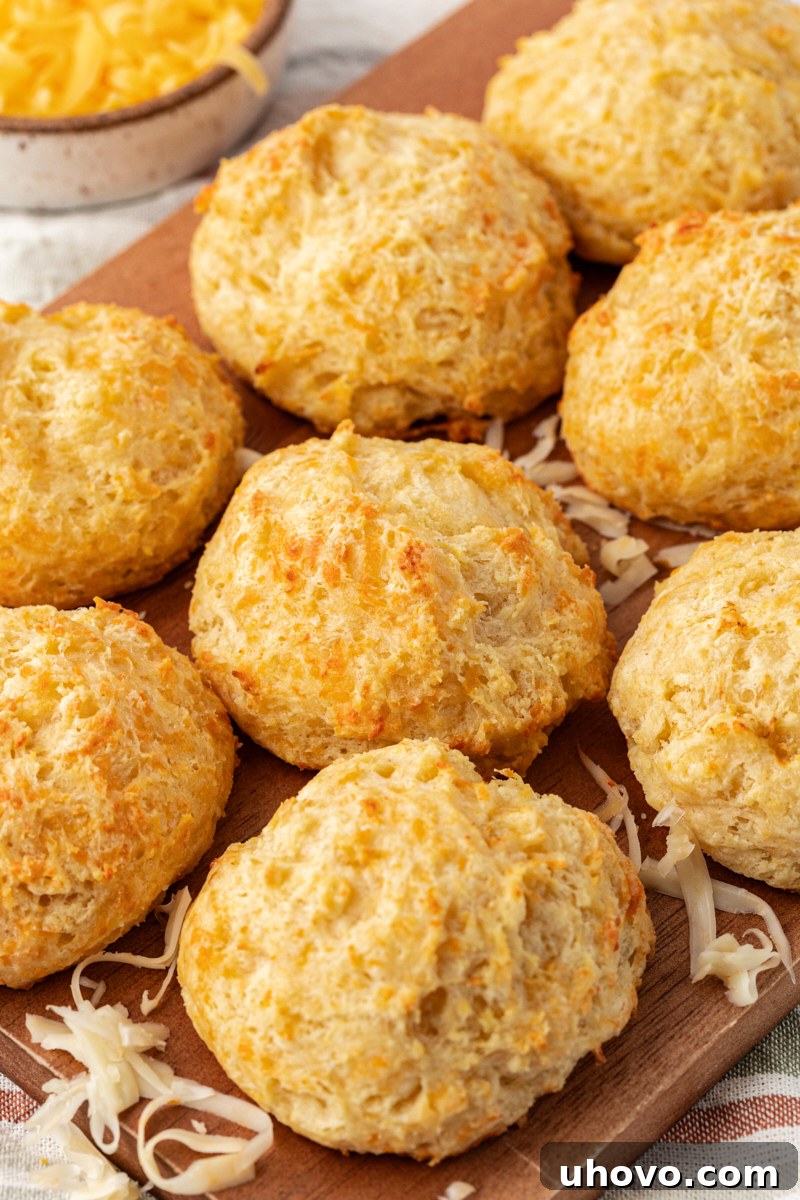 three cheese biscuits on a wooden serving board, showcasing their golden-brown tops and flaky texture