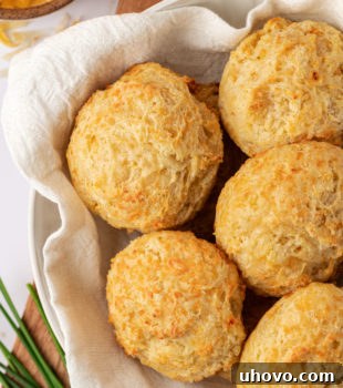overhead view of three cheese biscuits in a towel-lined bowl, ready to be served