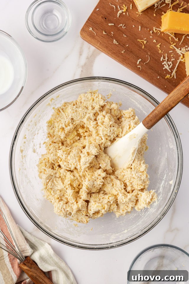 overhead view of buttermilk being poured into the biscuit dough in a glass mixing bowl, ready to be gently combined