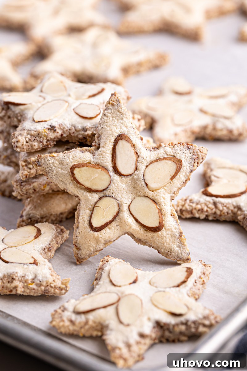 Beautifully baked German Zimtsterne cookies on a parchment-lined baking sheet, glistening with meringue