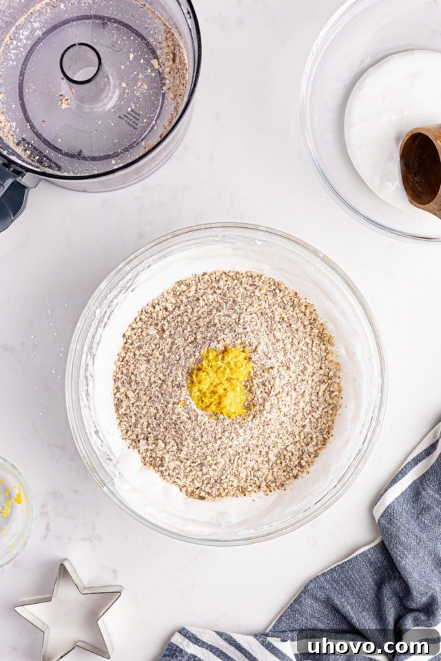 Lemon zest and ground almonds being gently folded into the whipped egg whites