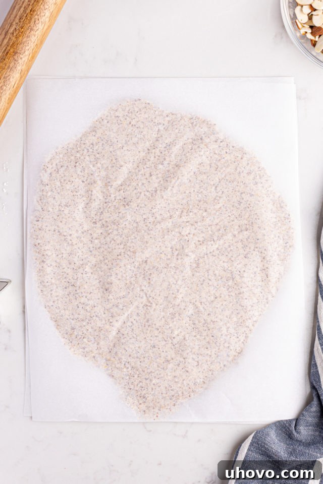 Overhead view of Zimtsterne dough rolled evenly between two sheets of parchment paper
