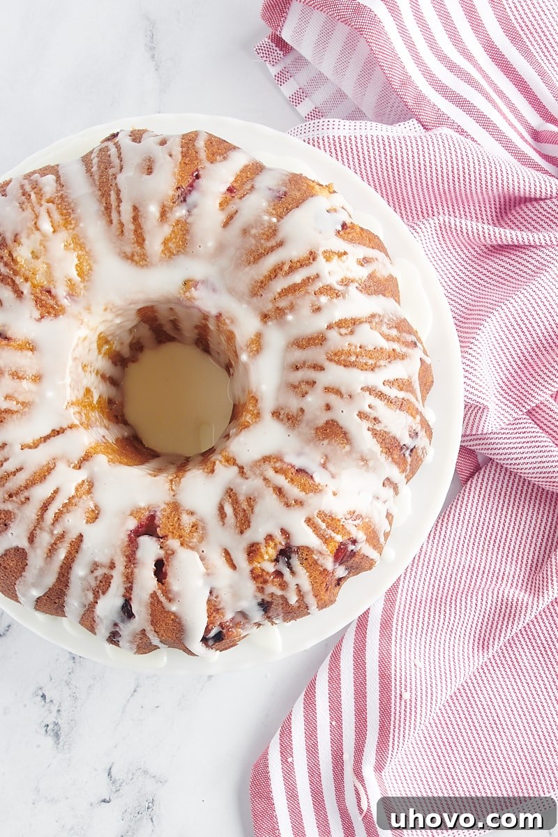 A beautifully glazed Cranberry Bundt Cake, with the white glaze evenly distributed and dripping down the sides.