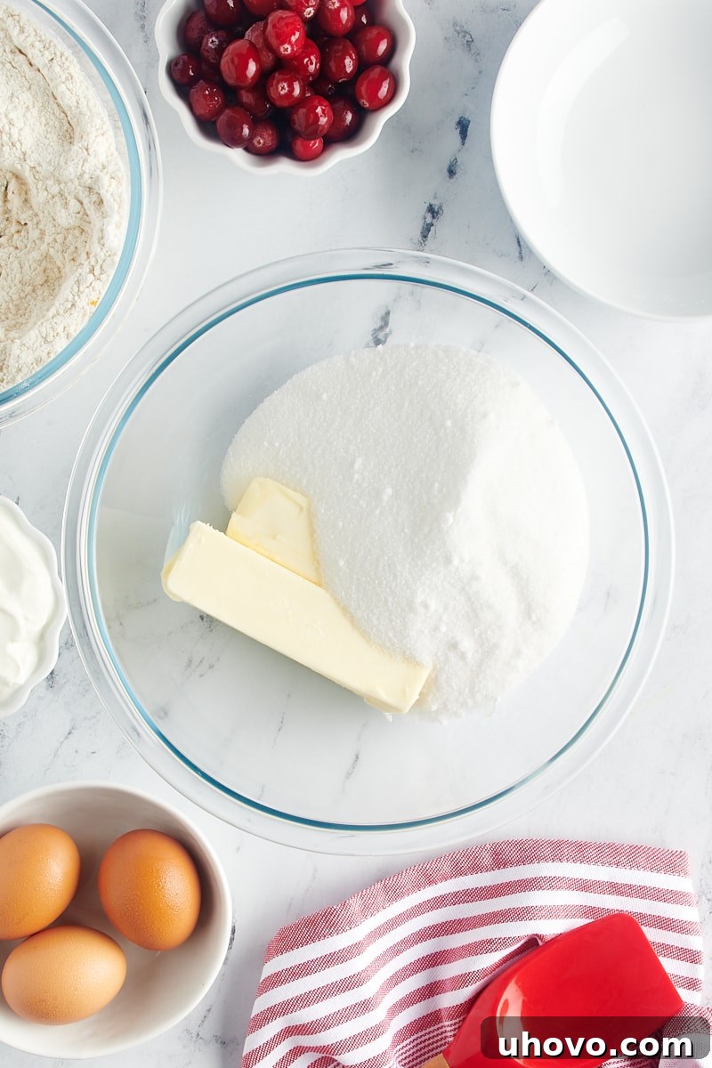 Uncreamed butter and granulated sugar in a glass mixing bowl before being beaten together.