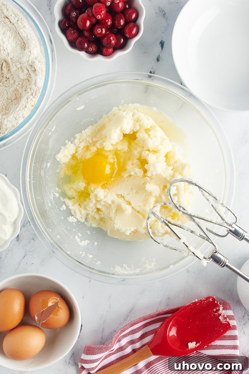 Adding individual eggs into the bundt cake batter during the mixing process, ensuring each is fully incorporated.