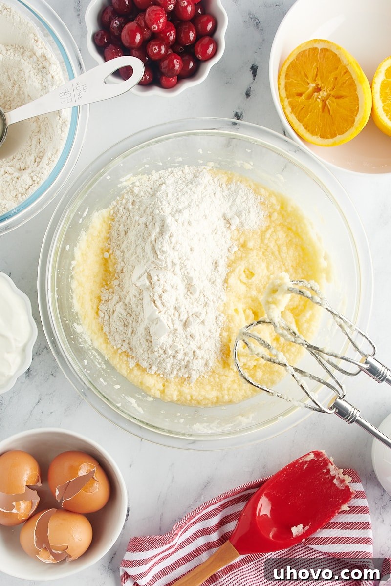 Adding the first portion of flour mixture to the wet cake batter in a mixing bowl.