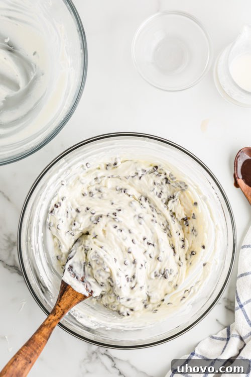 The completed chocolate chip cheesecake mixture, smooth and creamy in a glass bowl, ready to be spread over the brownie crust.