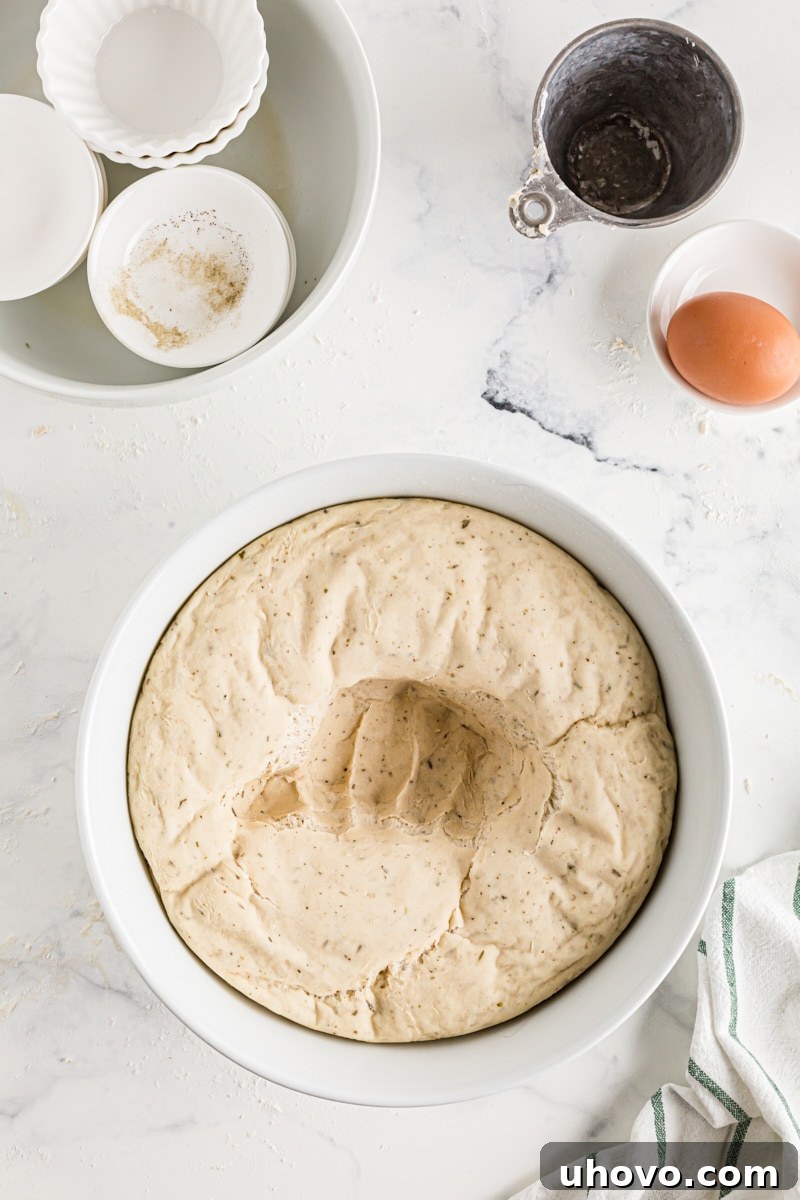 A hand gently punching down the risen dough in a bowl to release air.