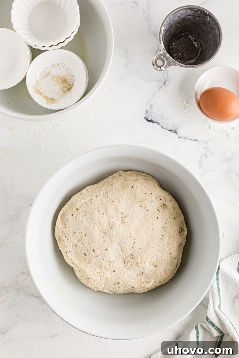 A bowl of Herb Cloverleaf Roll dough after being punched down, with the air released, ready for shaping.