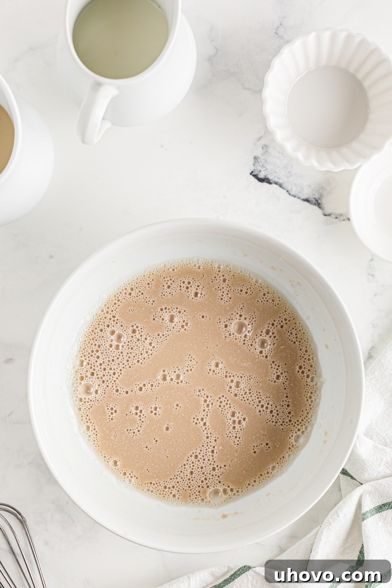 Active dry yeast blooming in warm water in a bowl on the counter, showing a foamy surface.