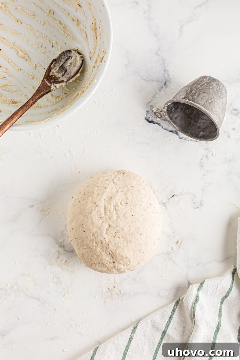 A perfectly smooth and elastic sphere of bread dough resting on a lightly floured counter after kneading.