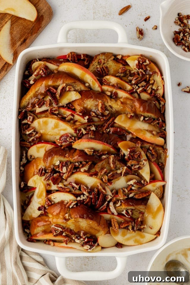Overhead view of apple cinnamon baked French toast in a baking dish, drizzled with the butter and brown sugar topping, ready to be baked.
