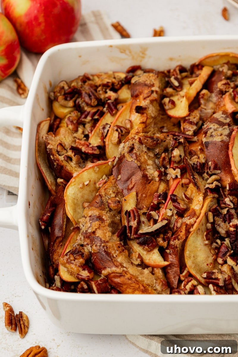 A warm baking pan filled with golden-brown apple cinnamon baked French toast, fresh from the oven, showing the crisp topping and soft interior.