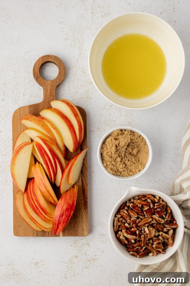 Overhead view of thinly sliced apples and chopped pecans, ready to be sprinkled over the chilled French toast bake.