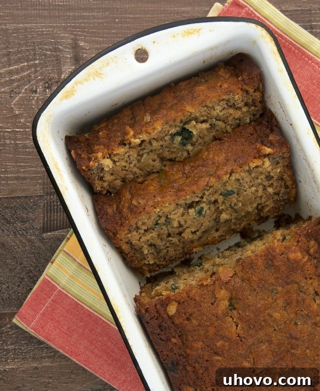overhead view of Granola Banana Bread in a white metal loaf pan, showcasing its golden-brown crust and chunky texture