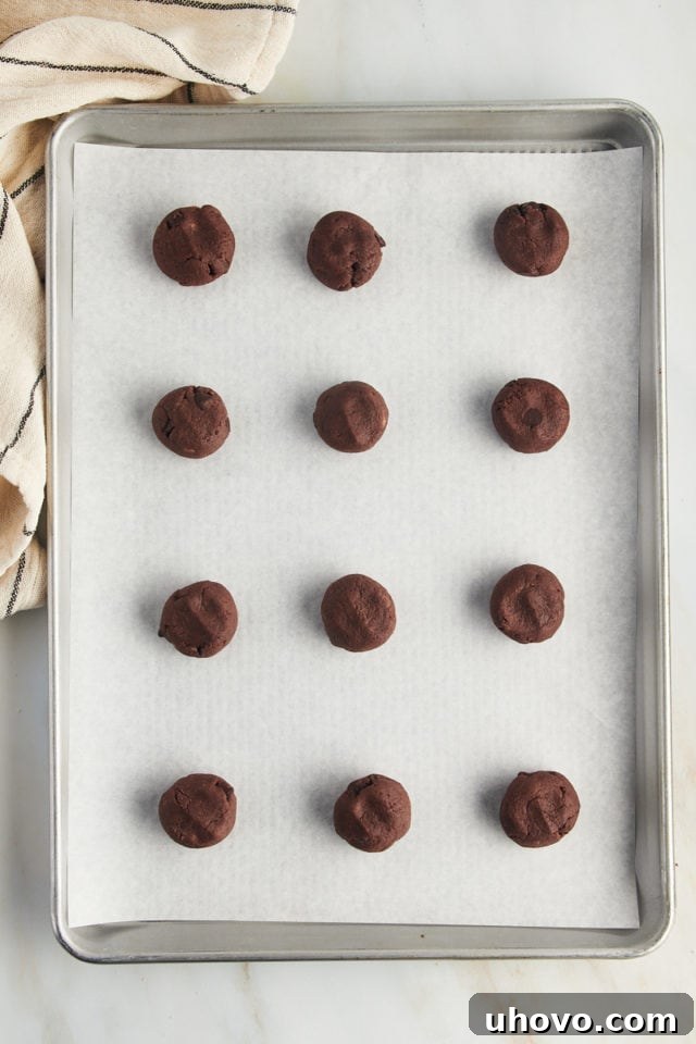 Overhead view of chocolate chocolate chip cookie dough balls on parchment-lined pan