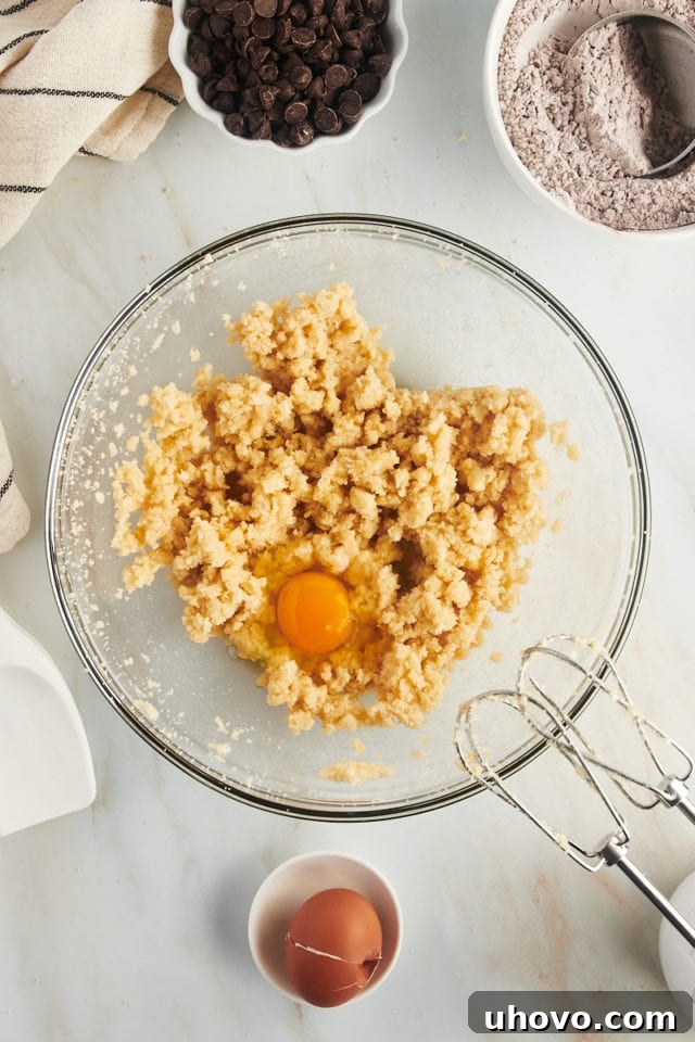Egg cracked into bowl of creamed butter and sugar