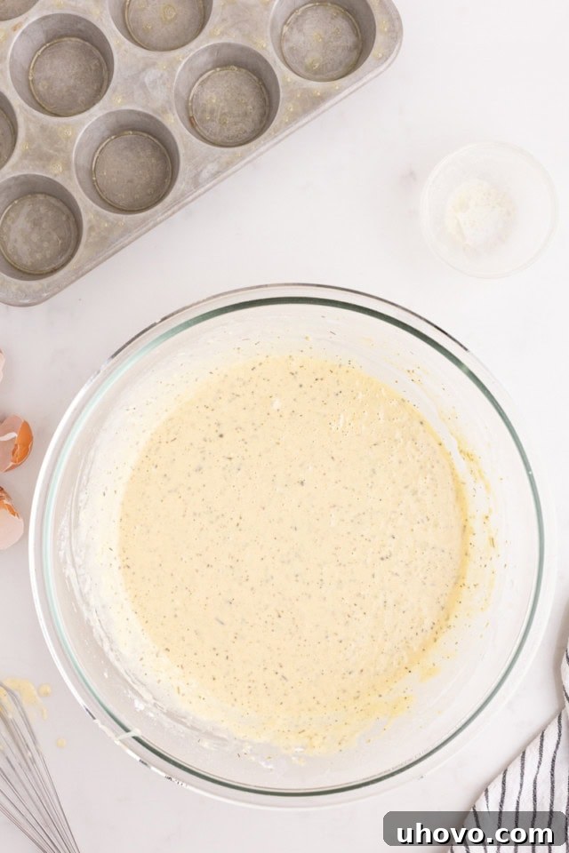 Overhead view of the smooth, frothy popover batter in a glass mixing bowl, ready for baking.