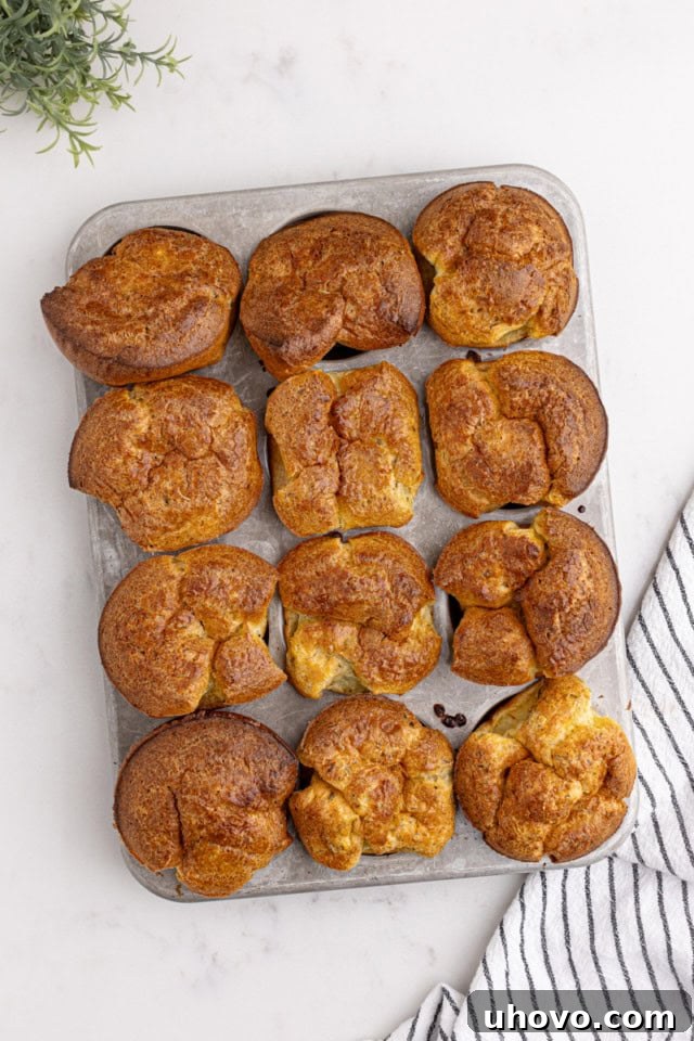 Overhead view of freshly baked, puffed popovers with golden-brown tops still in the muffin pan.