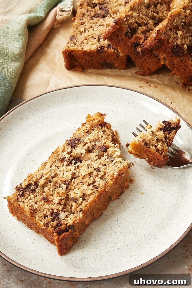 A perfectly baked slice of Chocolate Chip Oatmeal Quick Bread on a brown-speckled white plate