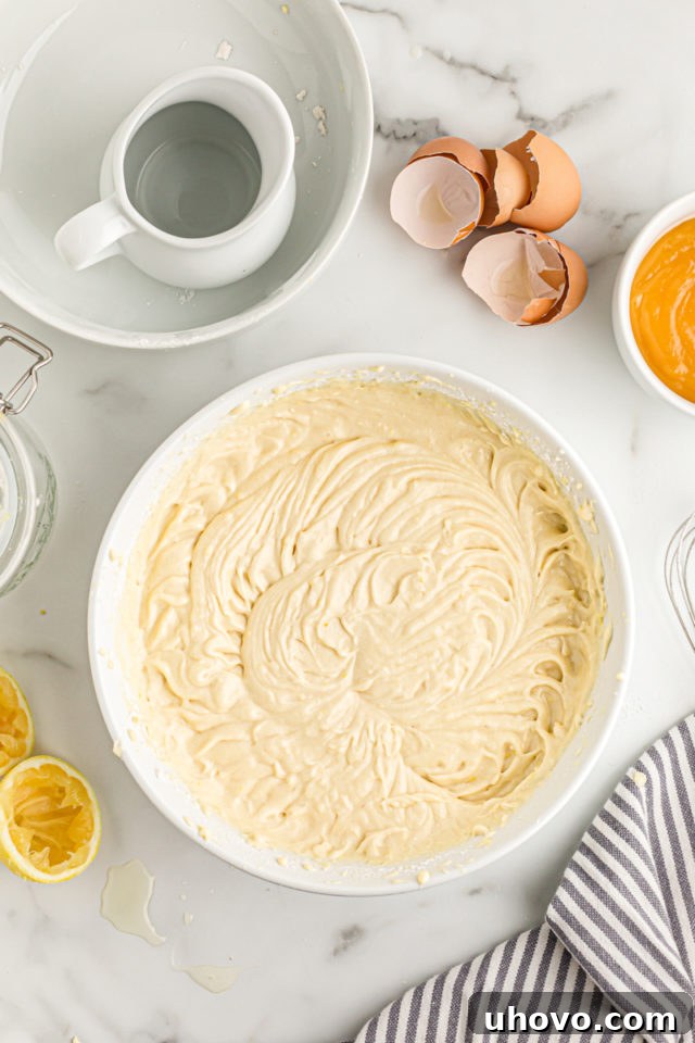 Overhead view of the fully mixed lemon cake batter in a large mixing bowl, smooth and ready for the cake pans.