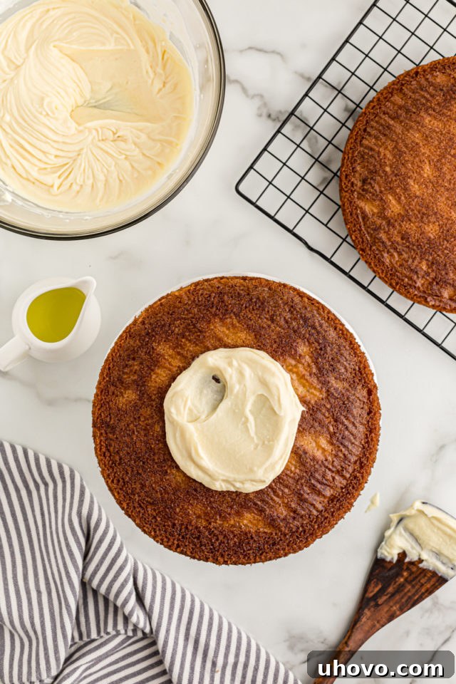 Overhead view of the first layer of lemon cake with a generous spread of creamy mascarpone frosting on top, ready for the second layer.