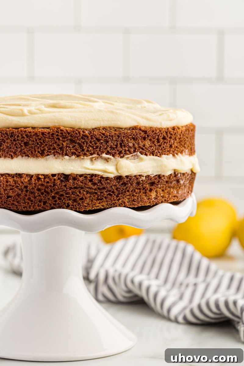 A beautiful whole lemon cream cake standing proudly on a cake stand, viewed from the side to clearly show its distinct, moist layers and fluffy frosting.