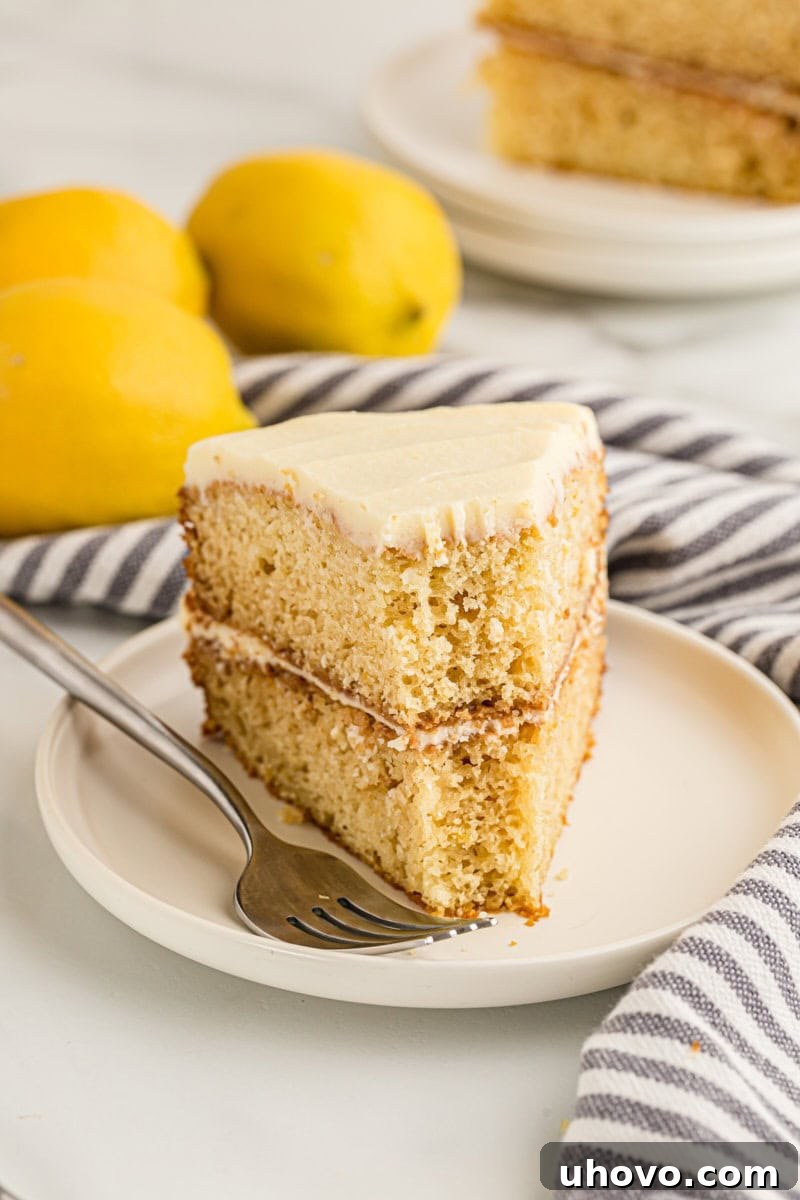 A tempting slice of lemon cream cake on a plate, with a small bite taken from the tip, highlighting its soft texture and creamy frosting.