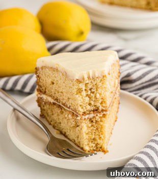 A tempting slice of lemon cream cake on a plate, with a small bite taken from the tip, highlighting its soft texture and creamy frosting.