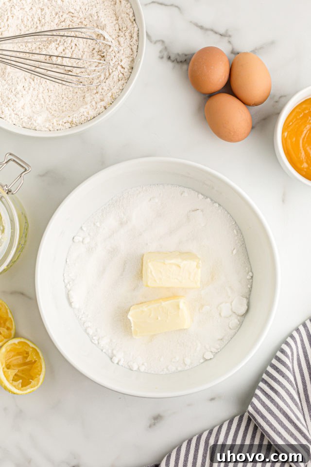 Overhead view of softened butter and granulated sugar being creamed together in a mixing bowl until light and fluffy.