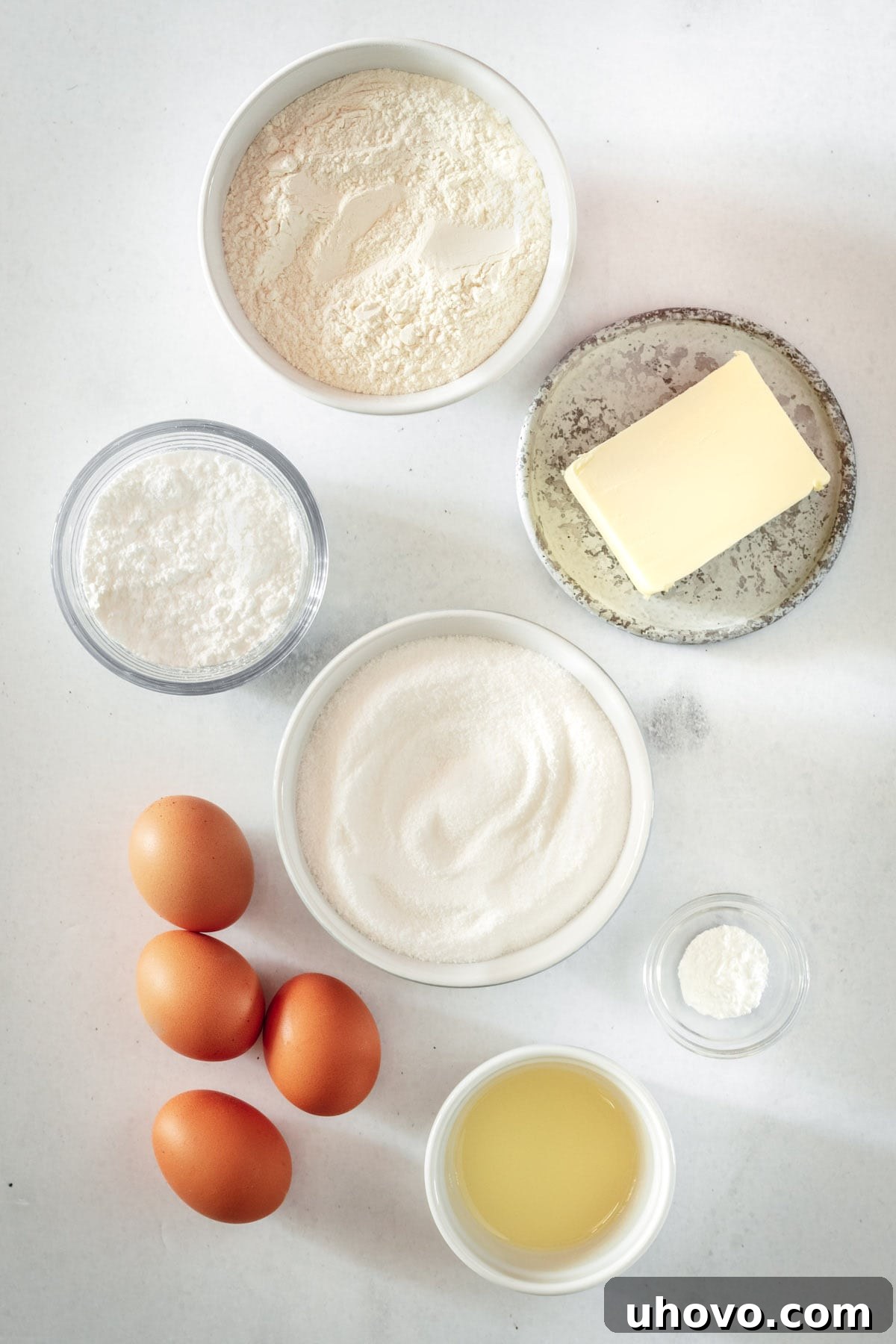 An overhead shot showcasing the fresh ingredients for lemon bars, including whole lemons, butter, eggs, flour, and sugar, laid out neatly on a kitchen counter.