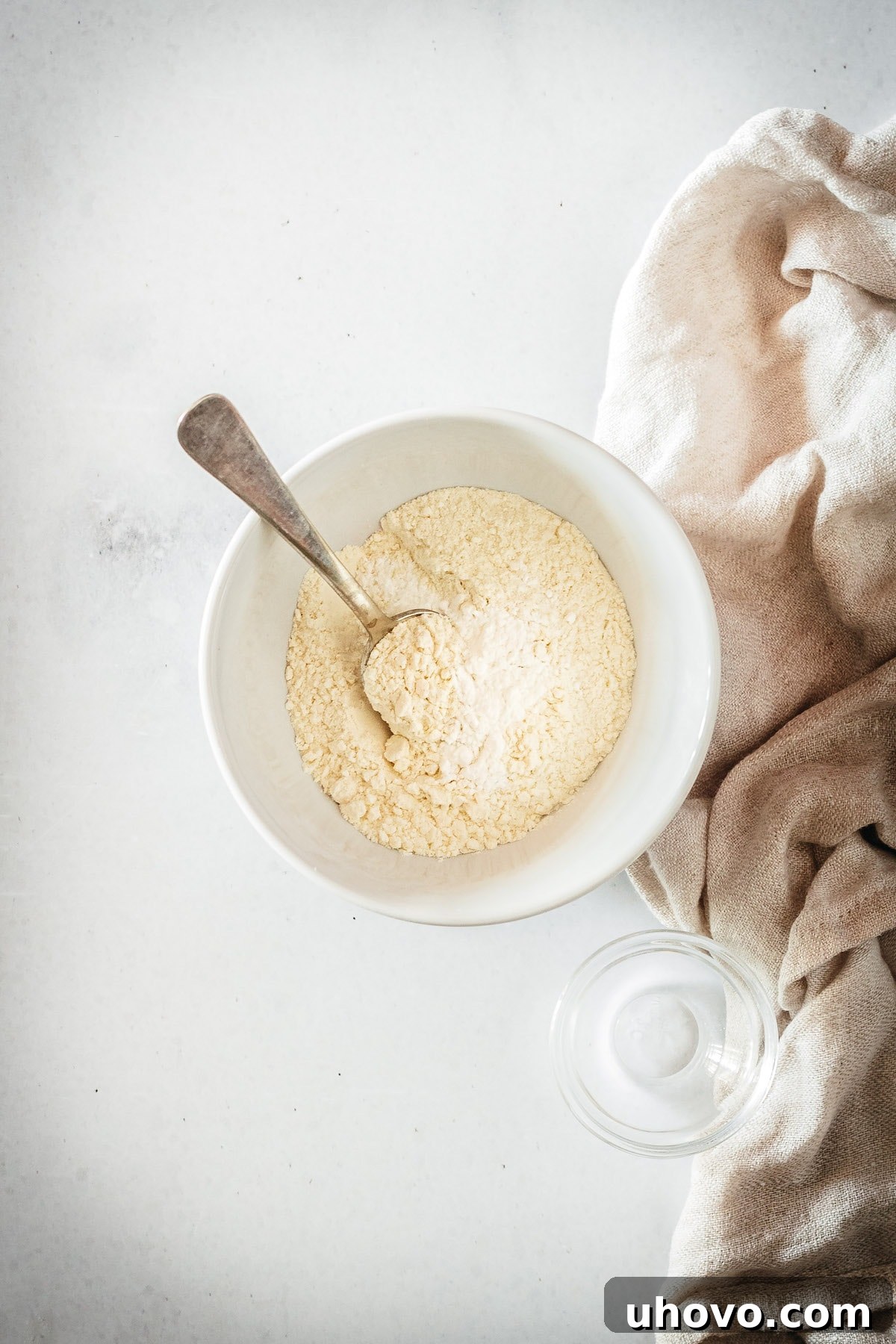Overhead view of the dry ingredients for the lemon filling (flour and baking powder) in a small bowl with a spoon, perfectly mixed.