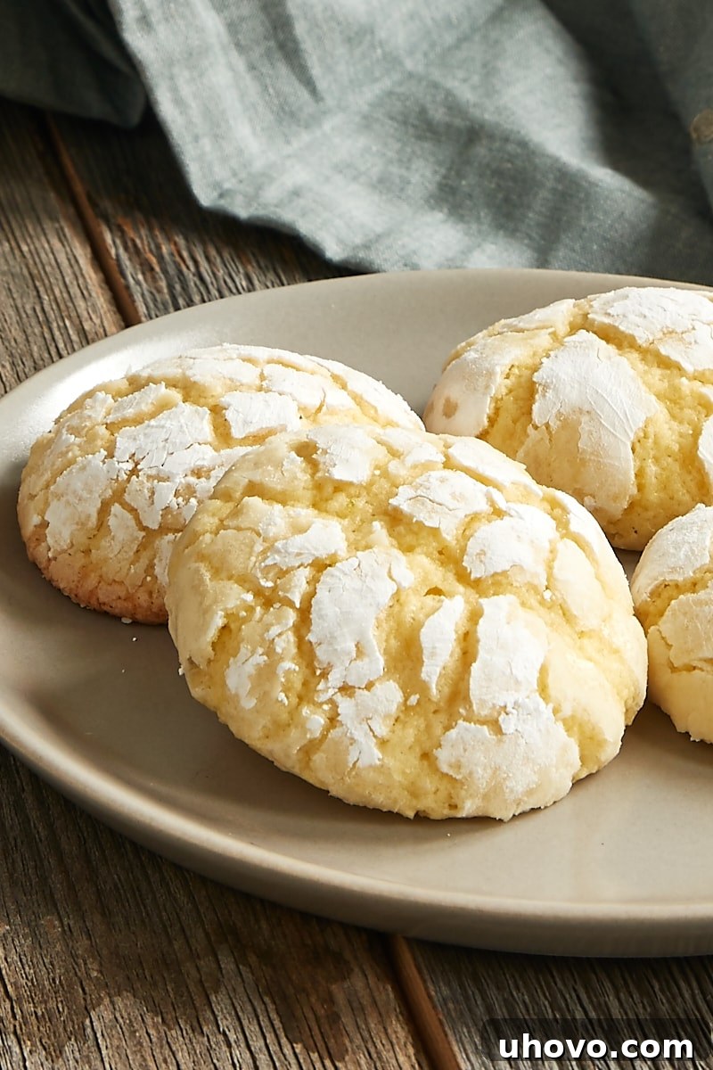 A cluster of Key Lime Crinkle Cookies arranged on a beige plate, highlighting their distinctive powdered sugar coating and delicate crinkled texture.