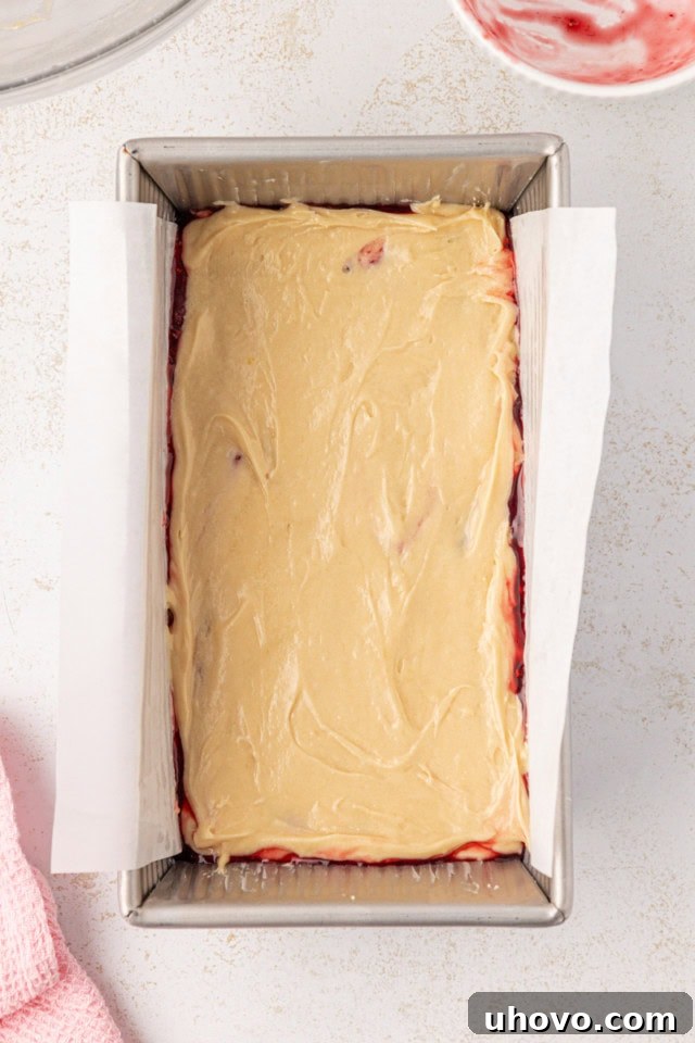 Overhead view of berry swirl pound cake batter in a loaf pan, perfectly swirled and ready to go into the oven.