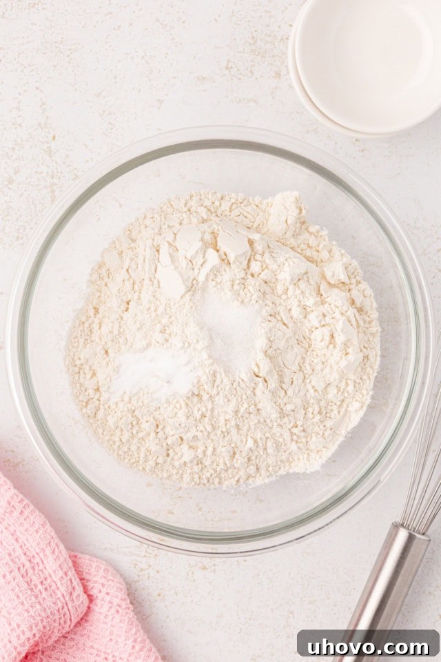 Overhead view of flour, baking soda, and salt in a glass mixing bowl, perfectly combined.