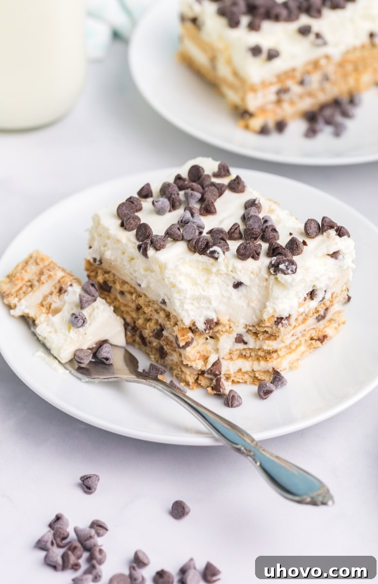 a slice of cannoli icebox cake on a white plate with a bite on a fork; another slice partially visible in the background