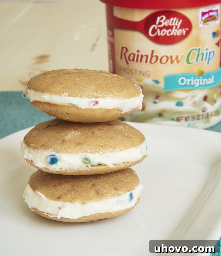 Delicious strawberry whoopie pies with colorful Rainbow Chip frosting filling are presented on a white plate. - Bake or Break