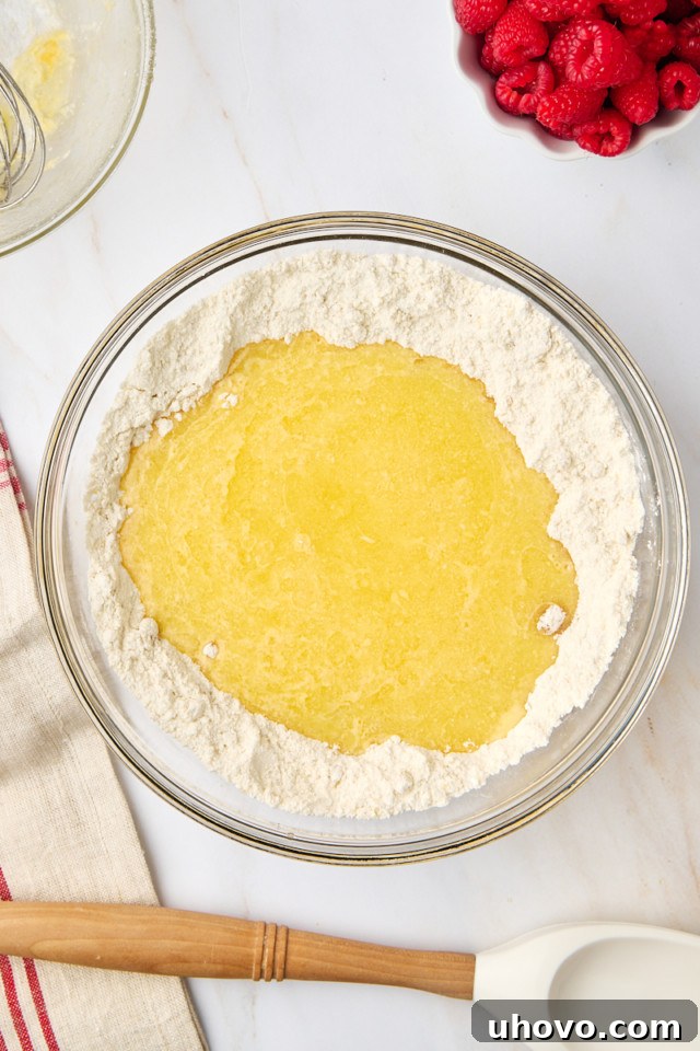 An overhead shot showing the wet ingredients being poured into the well of the dry ingredients in a mixing bowl, prior to mixing.