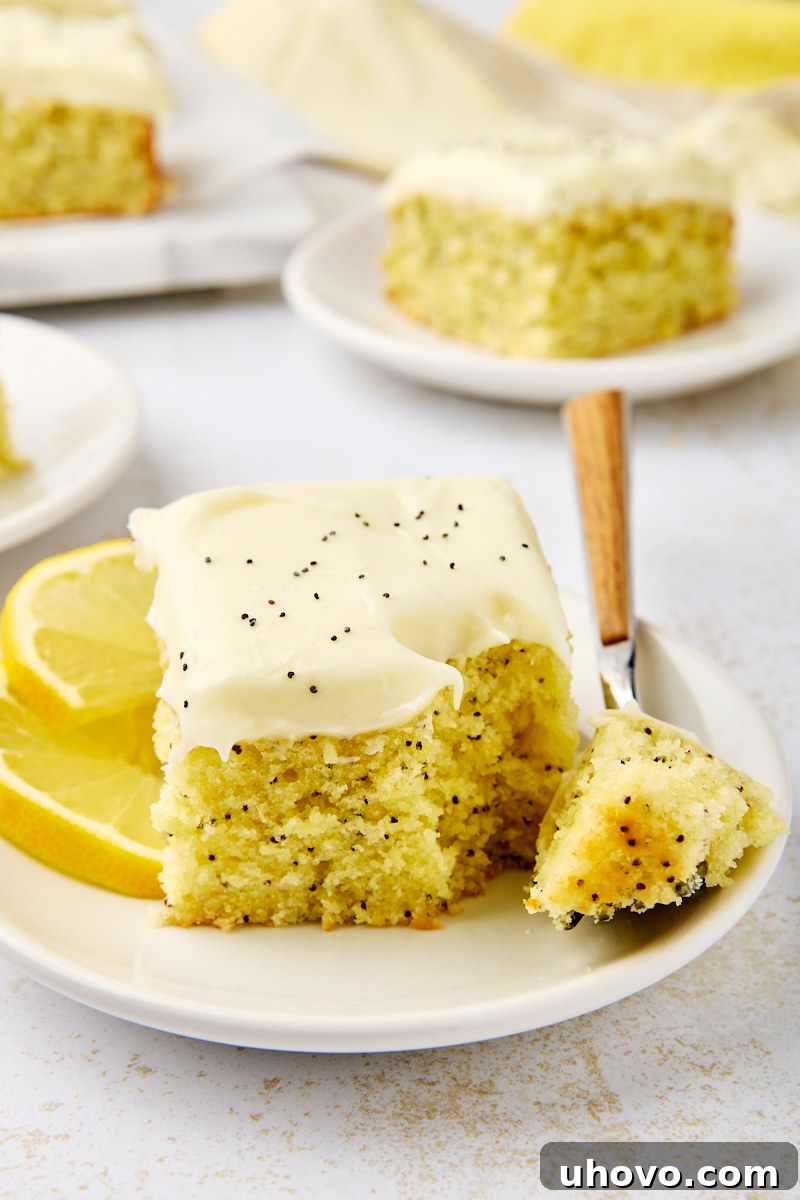 a slice of lemon poppy seed cake on a white plate with a bite on a fork